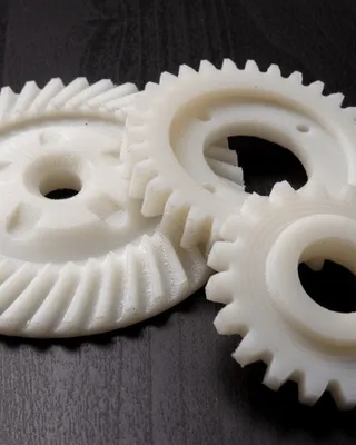 Trois engrenages en plastique blanc sur une surface sombre.