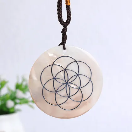 Pendentif rond en coquillage avec motif géométrique métallique suspendu à une corde noire.