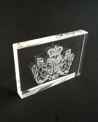 Une pièce en cristal avec un motif gravé représentant un blason royal avec deux lions et une couronne.