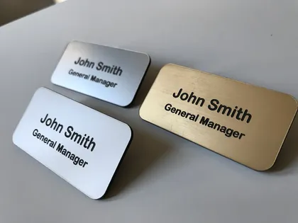 Trois plaques de nom pour John Smith, général manager, en différentes couleurs (argent, blanc et or)