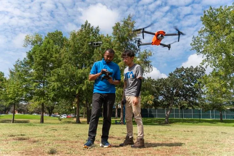Deux personnes pilotant un drone orange dans un parc
