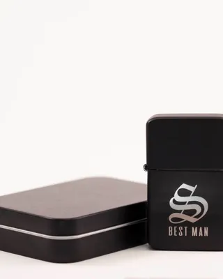 Une boîte en métal noire rectangulaire à gauche et un briquet noir avec un logo