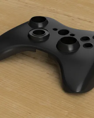 Manette de jeu vidéo noire sans boutons, placée sur un plan en bois.