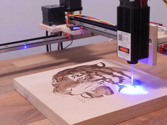 Une machine de gravure laser en train d'engraver le visage d'une femme sur une planche de bois.