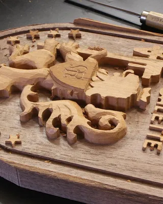 Un panneau en bois sculpté portant l'inscription "Edelweiss" et une figure de licorne, entouré de petites étoiles en bois, en cours de fabrication.