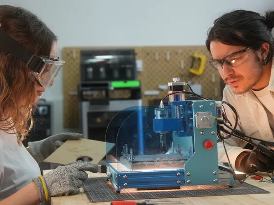 Deux personnes en laboratoire manipulant une machine de prototypage