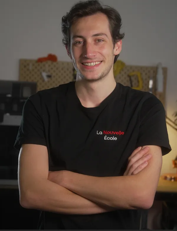 Jeune homme souriant avec un t-shirt noir, bras croisés dans un environnement intérieur