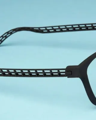 Lunettes noires avec des branches en forme de grille et un cadre en plastique noir sur un fond bleu clair.