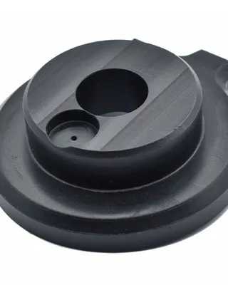 Pièce en plastique noir avec plusieurs trous et surfaces striées, probablement une partie mécanique ou un composant technique.