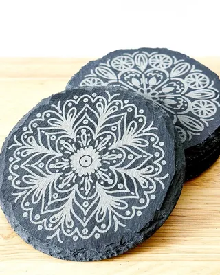 Assiettes en pierre noire avec motifs décoratifs blancs, posées sur une surface en bois.