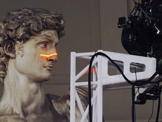 Une reproduction d'une statue antique avec un laser passant devant son nez, une caméra et un équipement technique à côté.