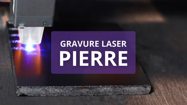 Une machine de gravure laser en action gravant une pierre. Le texte superposé indique 'Gravure Laser Pierre'.