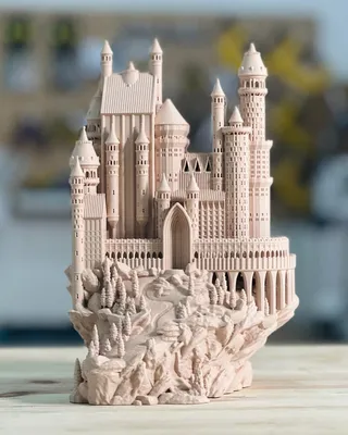 Modèle réduit d'un château féerique en blanc sur une table en bois, avec un décor flou en arrière-plan.