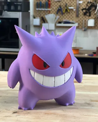 Statue en 3D de Gengar, un Pokémon violet avec un grand sourire, des yeux rouges et deux petites dents visibles.