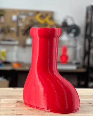 Objet en plastique rouge en forme de chaussette sur une surface en bois, fond d'atelier avec outils