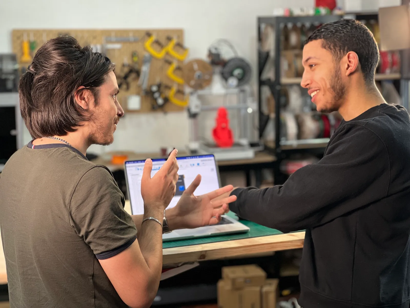 Deux jeunes hommes discutent dans notre atelier avec des ordinateurs portables
