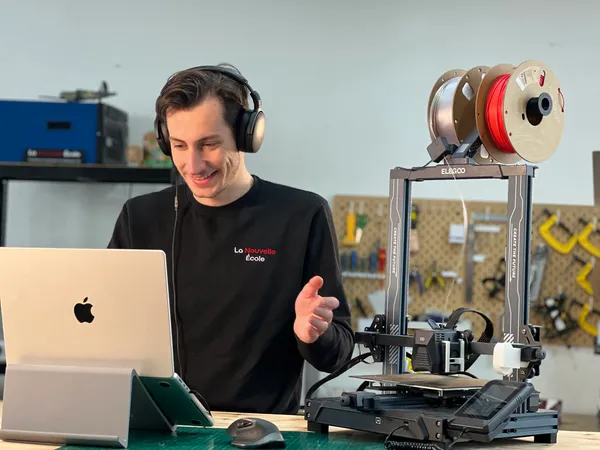 Femme souriante utilisant un ordinateur portable dans un atelier avec une imprimante 3D