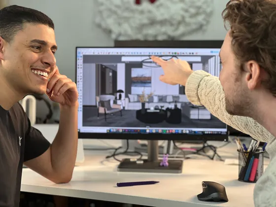 Deux hommes discutant devant un ordinateur montrant un intérieur design avec mobilier moderne.