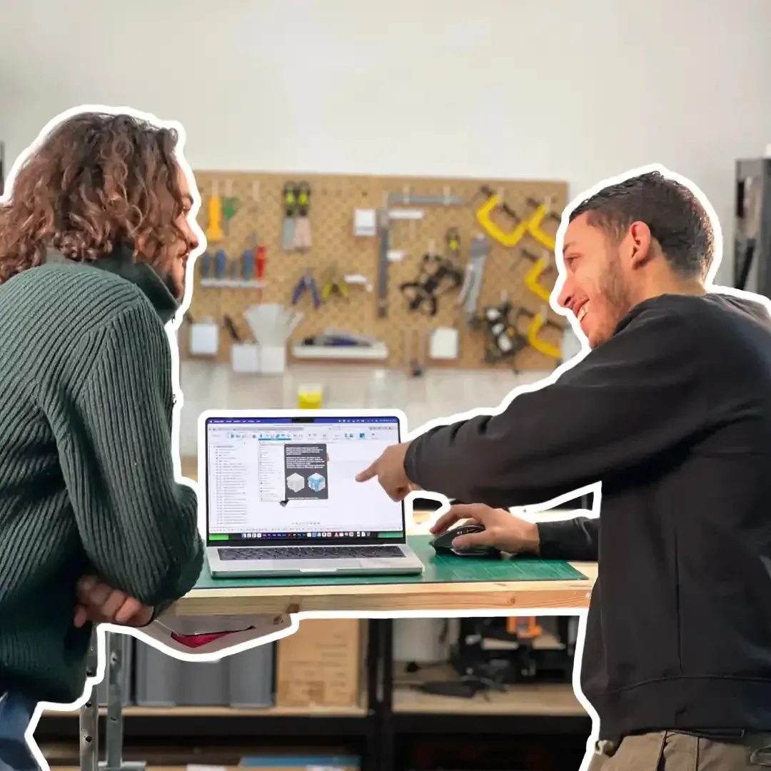 Deux personnes échangent devant un ordinateur portable dans un atelier
