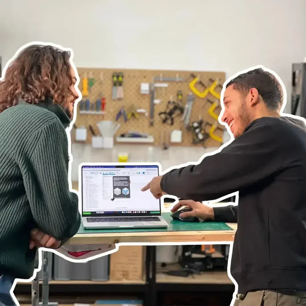 Deux personnes échangent devant un ordinateur portable dans un atelier