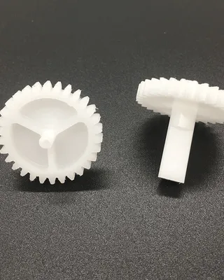 Deux engrenages en plastique blanc sur une surface noire.