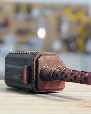 Modèle réduit d'une tourelle de canon de guerre en plastique rouge et noir posé sur une surface en bois, avec un fond flou.