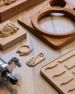 Outils et pièces en bois pour la gravure ou la sculpture sur bois, y compris une perceuse, des moulures en bois, et des plaques avec des motifs découpés.