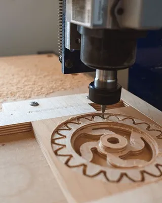 Une machine à CNC en cours de sculpture sur du bois, créant un motif complexe dans une pièce de bois.