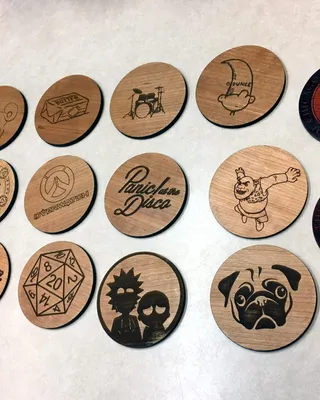 Image de vingt biscuits en bois gravés avec diverses illustrations et logos, disposés en quatre rangées sur une surface blanche.