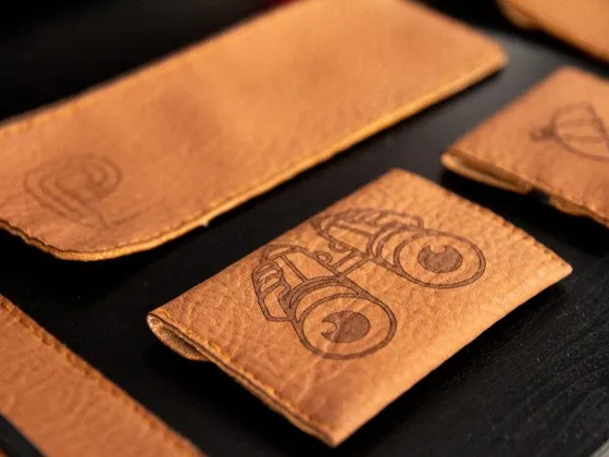 Pièces en cuir avec dessins d'engrenages et d'une lampe, posées sur une surface noire.