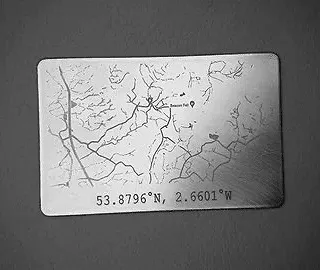 Carte en plastique avec coordonnées géographiques 53.8796°N, 2.6601°W et dessin de branches d'arbres