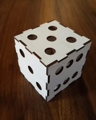 Cube en bois à trous avec des côtés assemblés par emplacement à gorge sur une surface en bois.