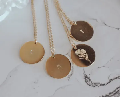 Trois colliers en or avec des disques gravés et une chaîne avec une chaîne gravée de fleurs.
