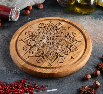 Plate en bois avec un motif mandala noir gravé au centre, entouré d'épices comme des graines de poivre, des étoiles de badiane, et des noix, sur une surface sombre.