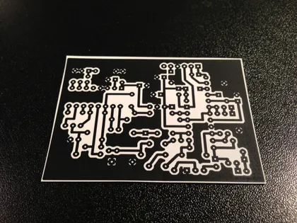 Circuit imprimé en noir et blanc avec tracés de composants électroniques.
