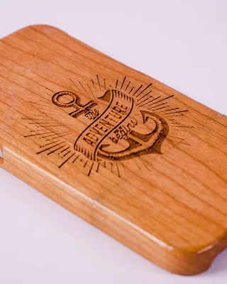 Planche en bois avec gravure d'une ancre, texte en français et illustrations du soleil.