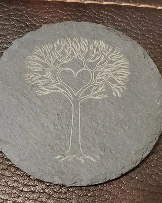 Dessous de verre rond en pierre avec gravure d'un arbre dont les branches forment un cœur.