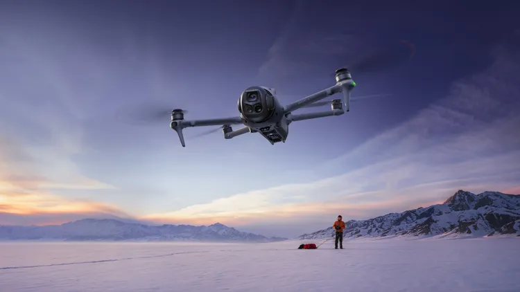 Drone volant au-dessus d'un paysage enneigé au coucher du soleil