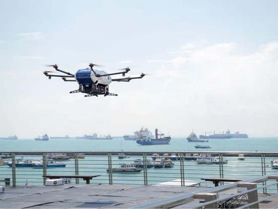 Un drone de surveillance volant au-dessus d'un port avec des navires et des bateaux en mer.
