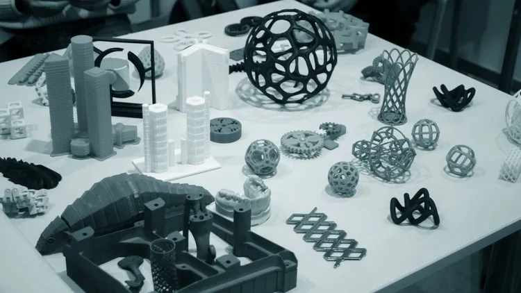 Table couverte de nombreuses pièces et maquettes imprimées en 3D