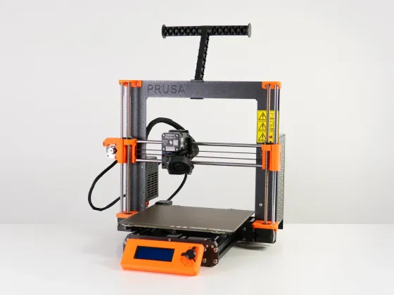 Imprimante 3D avec cadre en métal, plateforme d'impression, moteur, et écran de contrôle orange, sur une surface blanche.