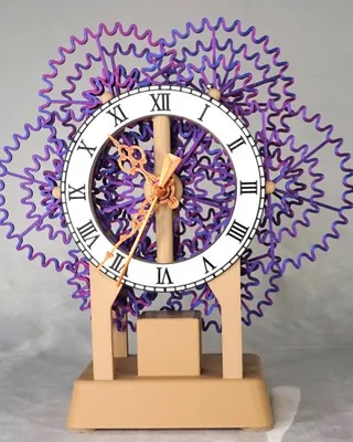 Une horloge décorative avec un cadre en forme de fleurs violettes stylisées, chiffres romains, et aiguilles dorées, posée sur une base en plastique beige.