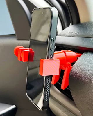 Un téléphone portable fixé avec un support rouge sur un tableau de bord de voiture.