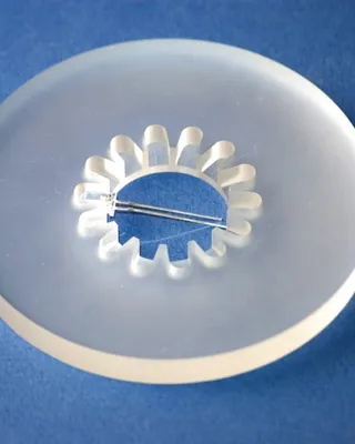 Plaque en acier inoxydable avec un trou en forme de clé et deux épingles à cheveux à l'intérieur, sur un fond bleu.