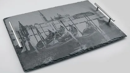 Tablette en pierre avec une gravure en noir et blanc d'un port avec des bateaux et des bâtiments.