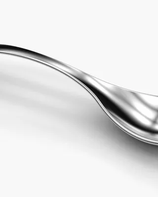 Une cuillère en métal brillante sur fond blanc