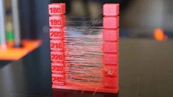 sur l'image on voit une piece imprimé en 3D avec beaucoup de stringing