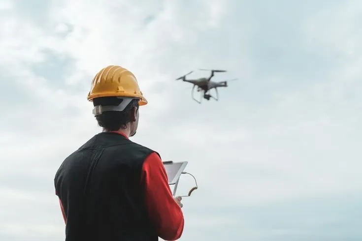 Professionnel du bâtiment pilotant un drone pour inspecter un chantier