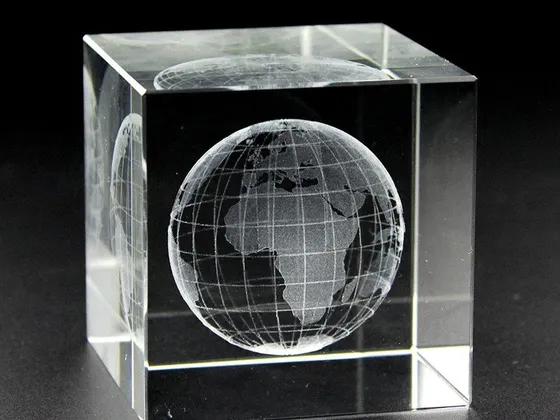 Cube en cristal transparent avec une gravure du globe terrestre au centre.
